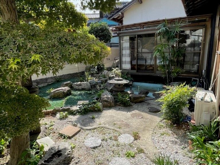 池がある庭にはモミジなどが受けられ、三角屋根が付いた一軒家がある。