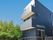 黒を基調とした3階建ての建物の側面から見た様子。玄関には手すり付きのスロープがある。