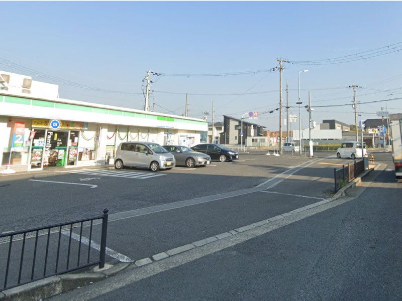 広い駐車場が付いたコンビニエンスストア。駐車場に複数台の車が止まっている。