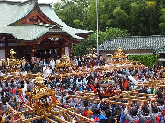 大きな神輿を大勢で運んでいるグループが５組いて、モスグリーンの屋根の社がある。