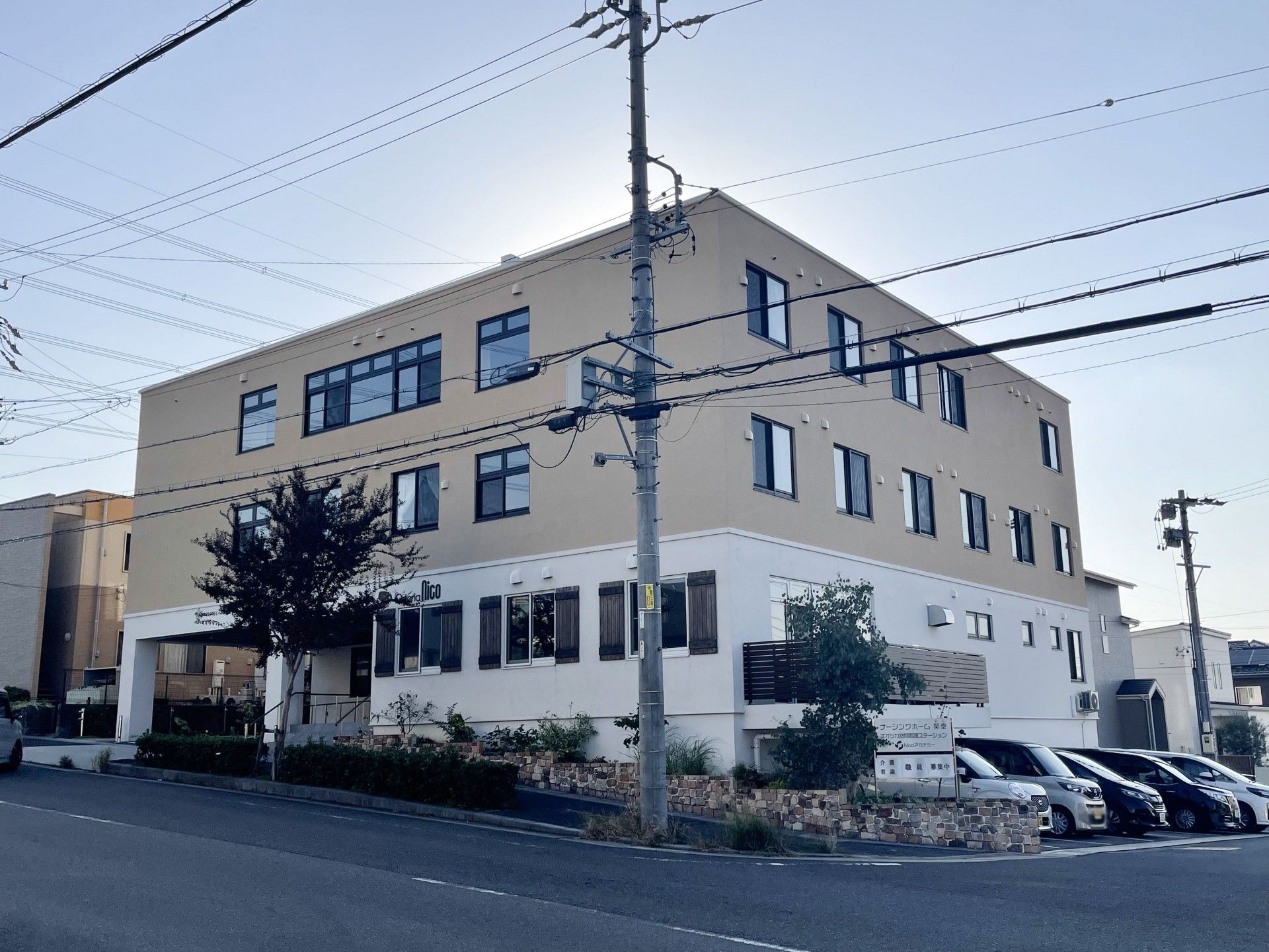 1階が白、2階と3階が茶色い外壁の3階建て建築物