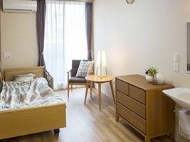 タンスや寝具付きベッド、エアコンなどがあるフローリングの部屋。