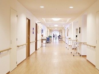 まっすぐな廊下の中央に2名の人が立っている。両サイドに手すりが付き、幅が広い廊下。