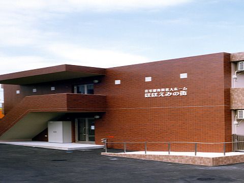 ブラウン系の2階建ての建物の外壁にはホーム名が書かれていて、大きな屋外階段も設置されている。