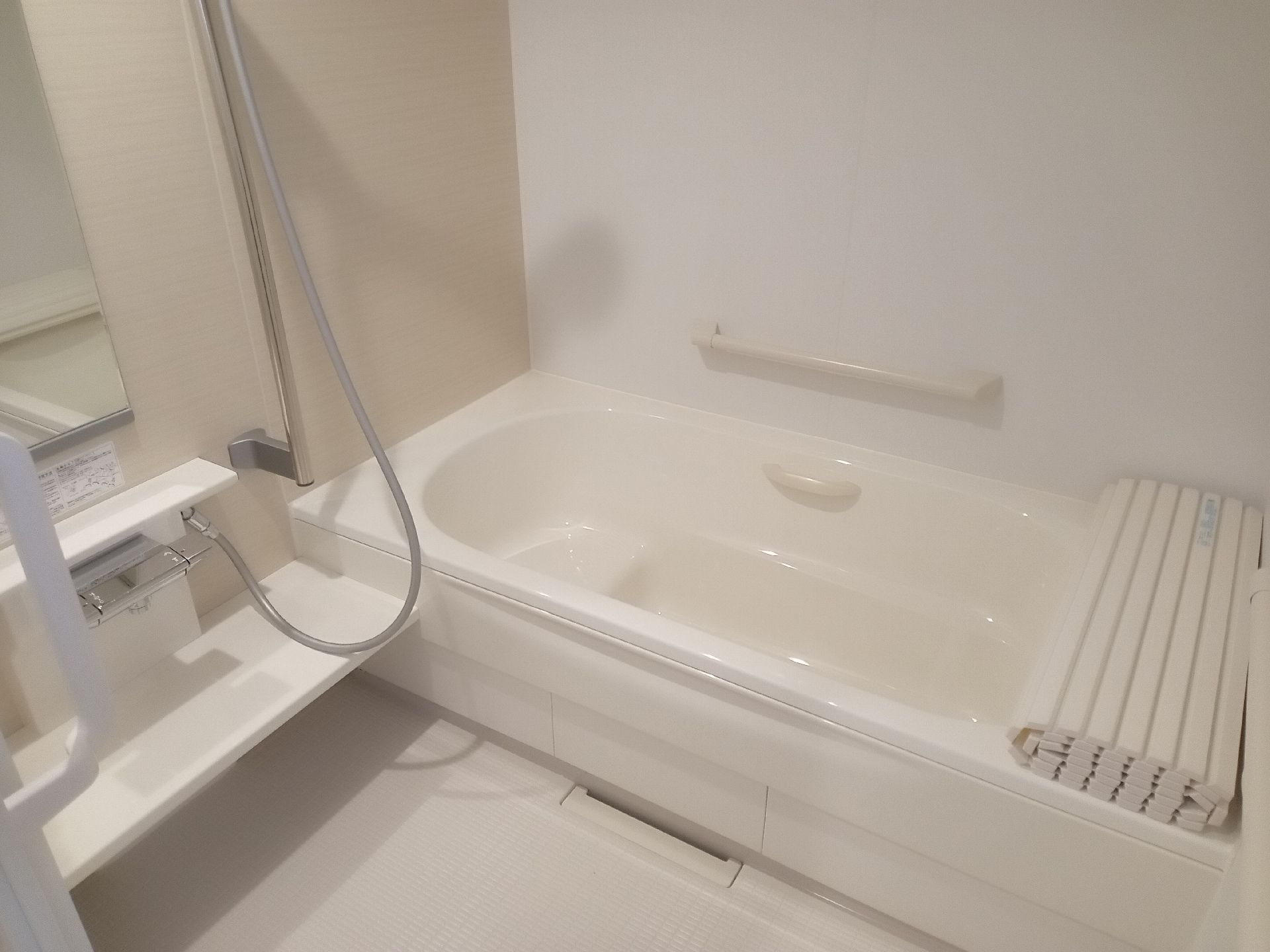 一人用の浴槽が設置された浴室には手すりやシャワーもあり、鏡も付いている。
