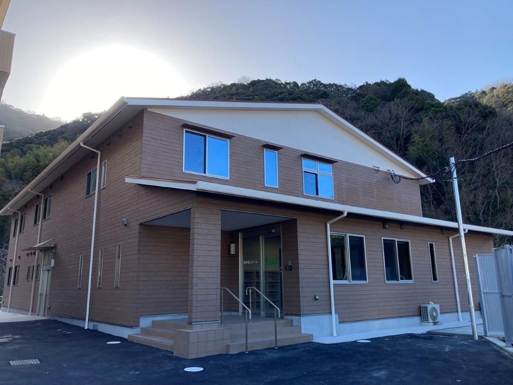 原っぱを散歩しているエプロンを付けた女性スタッフと高齢女性。