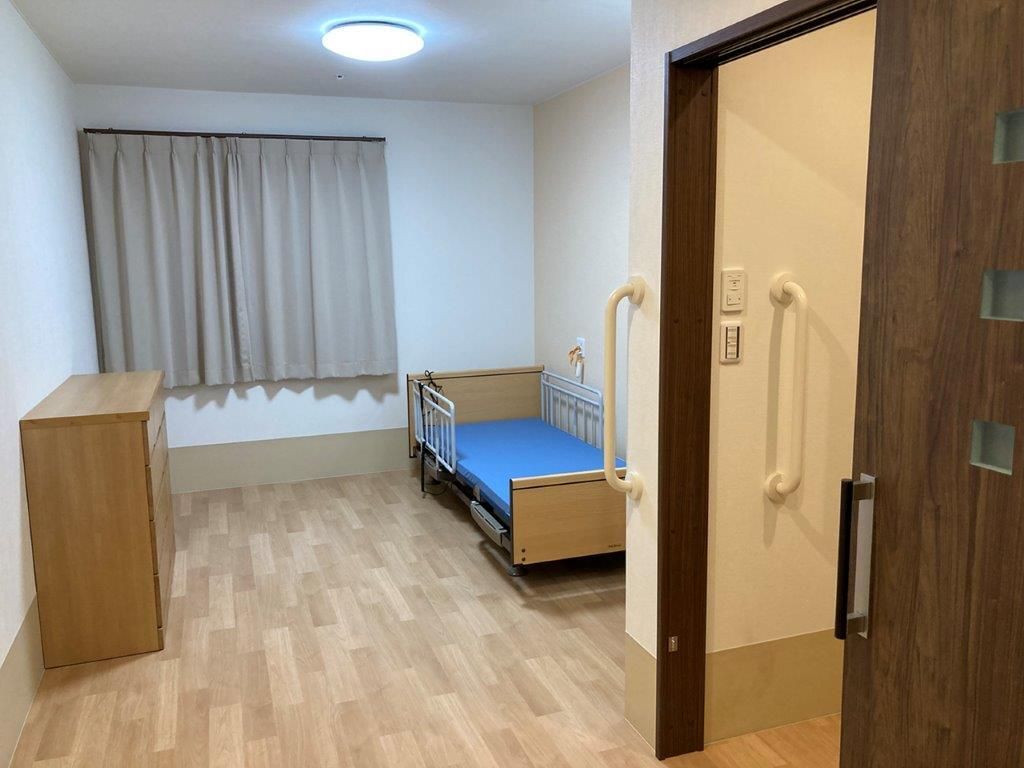 福祉車両から降りようとしている眼鏡をかけた高齢男性とサポートしている若いスタッフ。