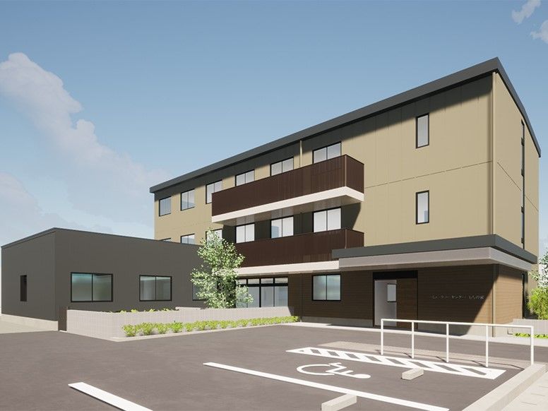 広い駐車スペースがある、茶色い外壁の3階建て建築物