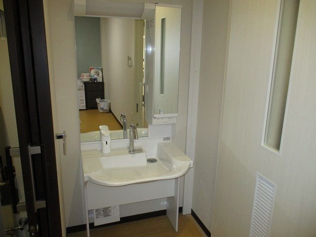 大きな鏡が付いた車いす対応の洗面所が設置された部屋。水が飛び散りにくいワイドタイプ。