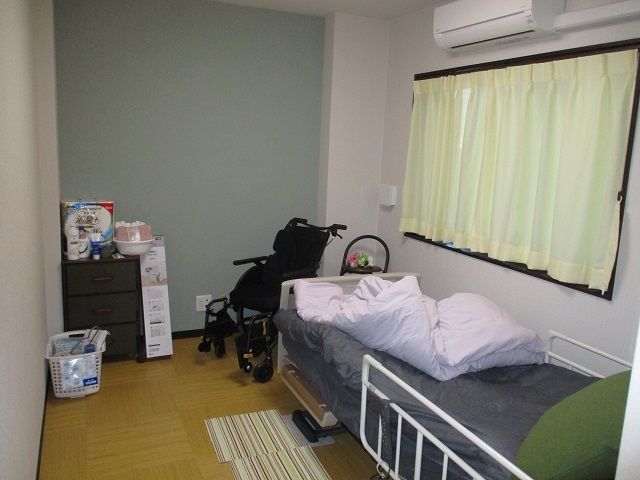 エアコンを設置した部屋には寝具付きベッドや車いすが置かれ、私物も持ち込まれている。