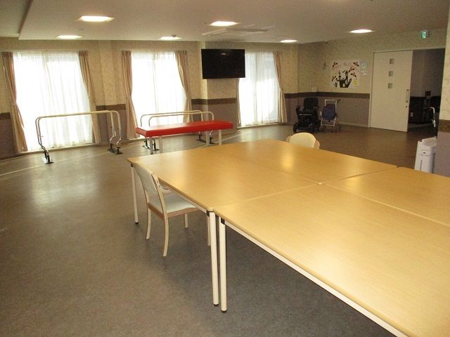 テレビが設置されている部屋にはダイニングテーブルが置かれていて、レースカーテンとカーテンが付いた窓がある。