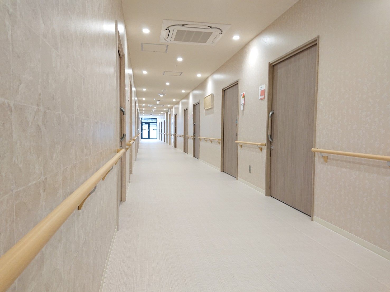 周囲を木々で囲まれた、茶色と白の外壁の4階建て建築物