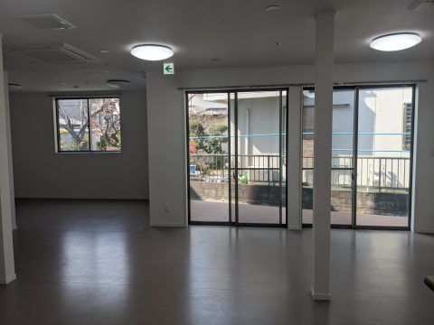 カーテンのない大きな窓が付いた共有スペースには家具などはなく、照明が点いている。