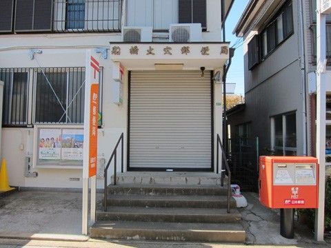 建物前に四角く赤いポストが設置された郵便局の外観