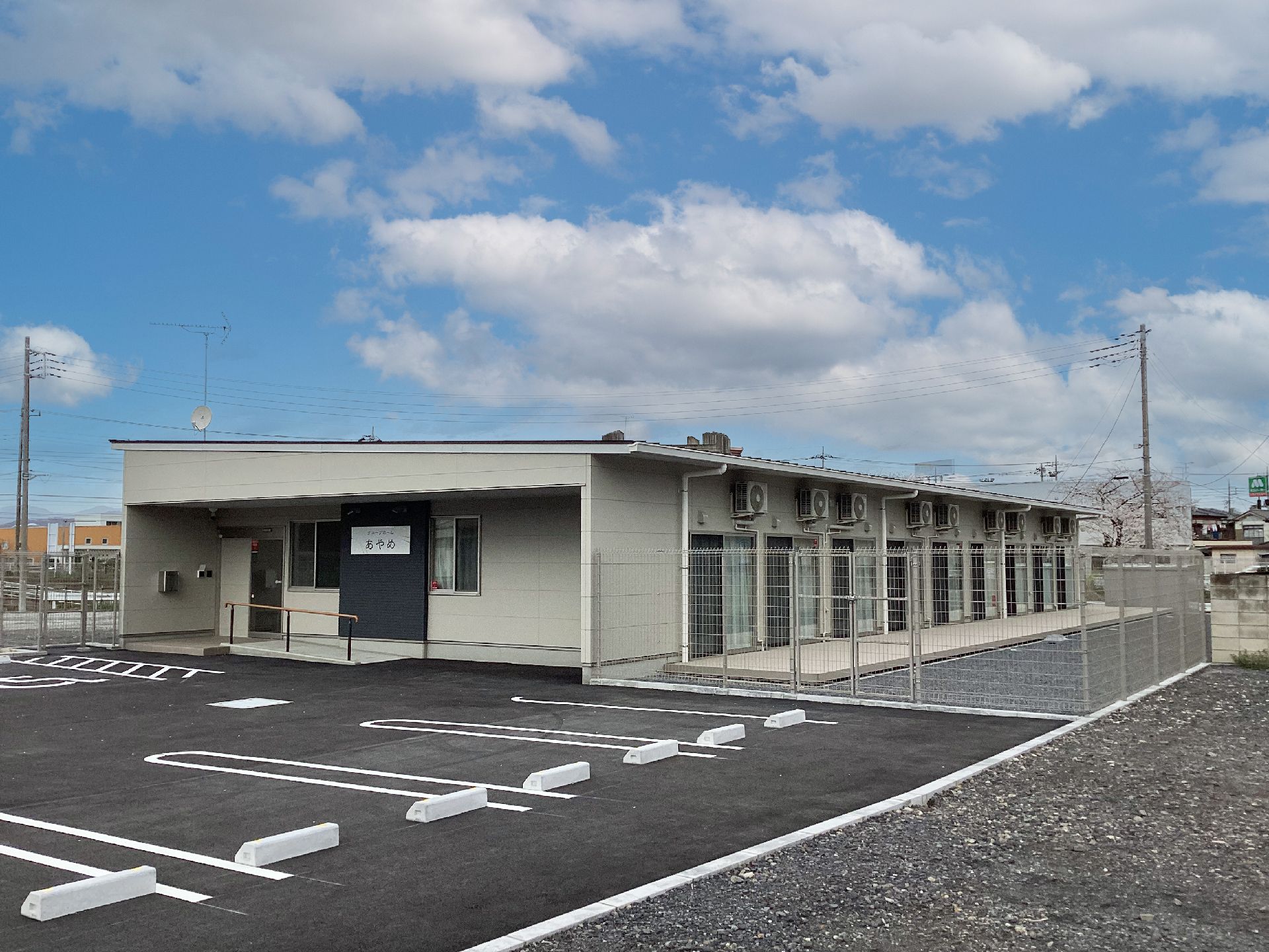 広い駐車場が付いた平屋建ての建物は日当たりのいい場所に建っている。