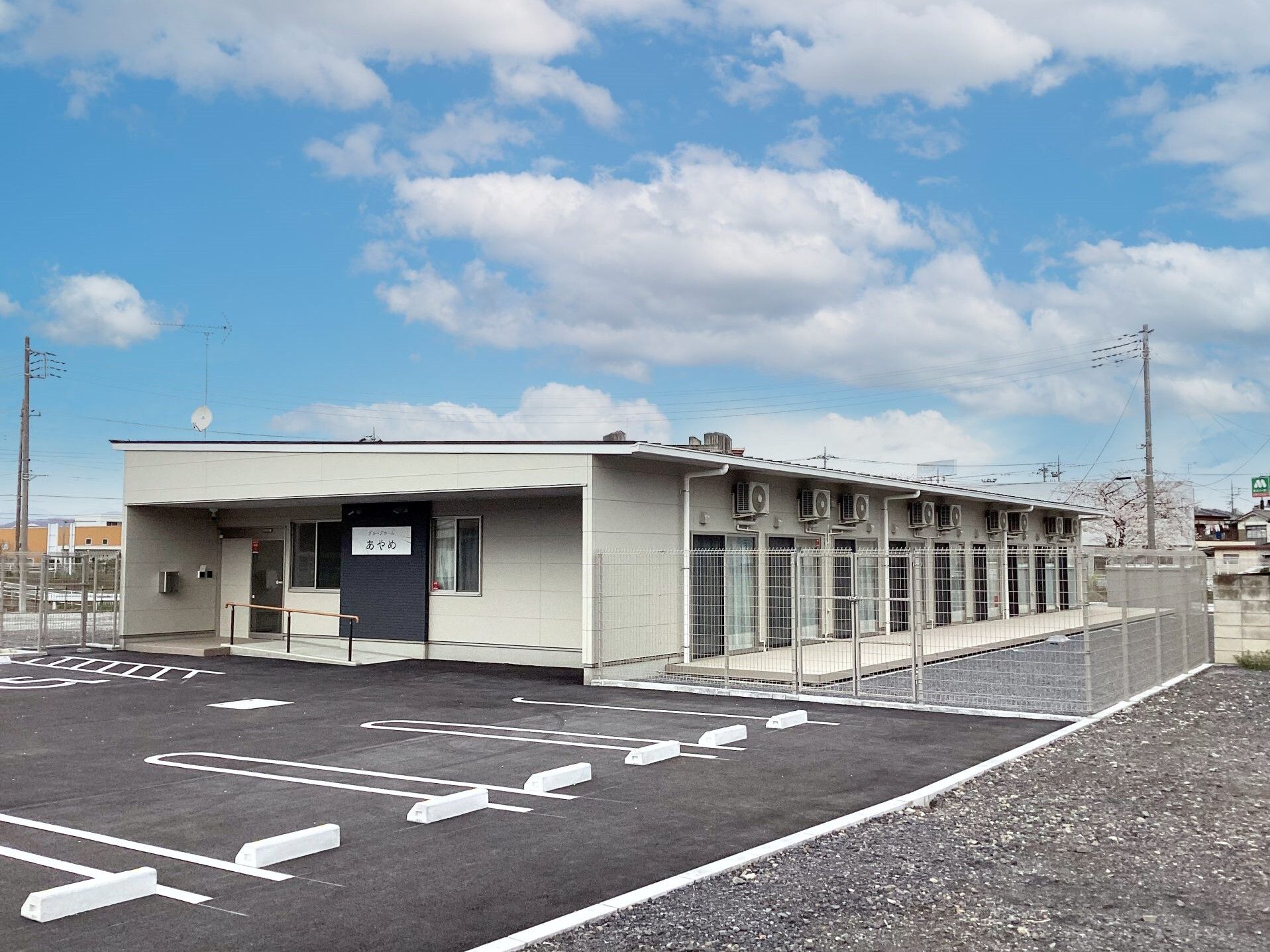 広い駐車場が付いた平屋建ての建物は日当たりのいい場所に建っている。