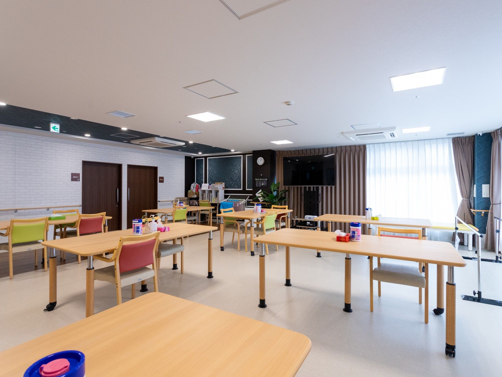 笑顔で遠くを指さす車いすの高齢女性に寄り添い笑顔でいるエプロンを付けた女性スタッフ。