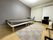 住宅が奥にあり、緑がある屋外で笑顔で話している車いすの高齢男性と付き添いのポロシャツを着た女性スタッフ。