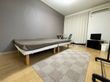 住宅が奥にあり、緑がある屋外で笑顔で話している車いすの高齢男性と付き添いのポロシャツを着た女性スタッフ。