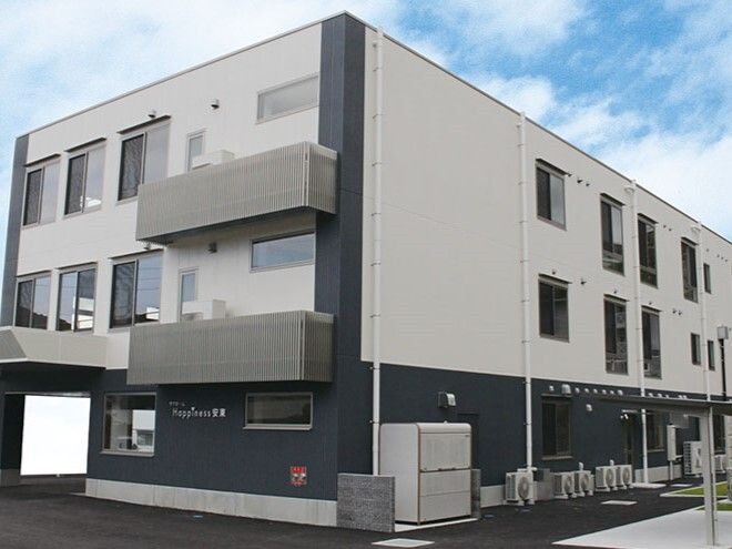 3階建ての建物の各フロアにベランダもあるグレーの外壁の建物。