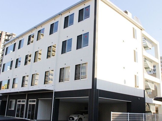 白を基調とした4階建ての建物にはたくさんの窓があり、側面には屋外階段が設置されている。