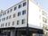 白を基調とした4階建ての建物にはたくさんの窓や屋外階段が設置され、玄関には屋根がある。