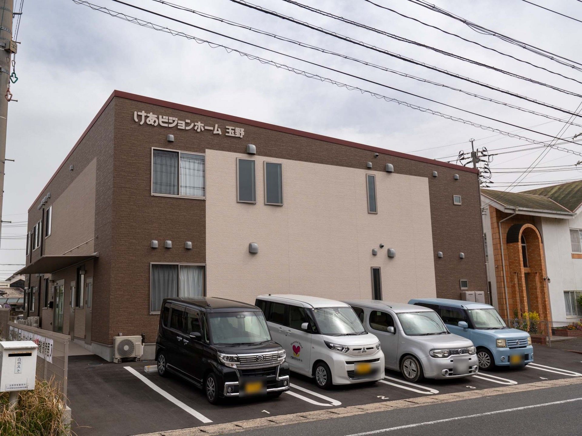 エプロンを付けた若い女性スタッフに手伝ってもらいながらフラワーアレンジメントをしている眼鏡をかけた高齢男性。