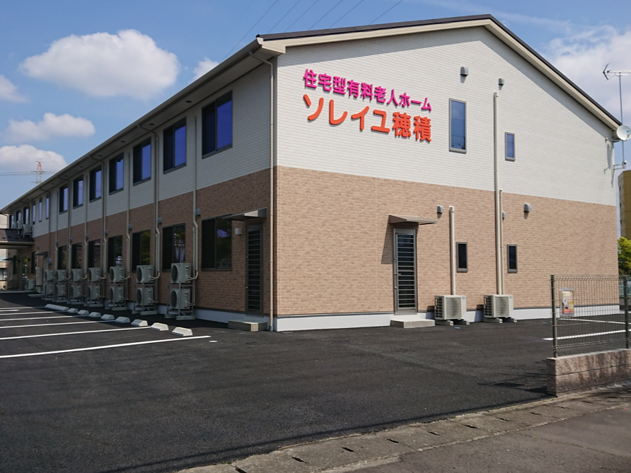 外壁に「住宅型有料老人ホームソレイユ穂積」を書かれている2階建てで三角屋根の建築物