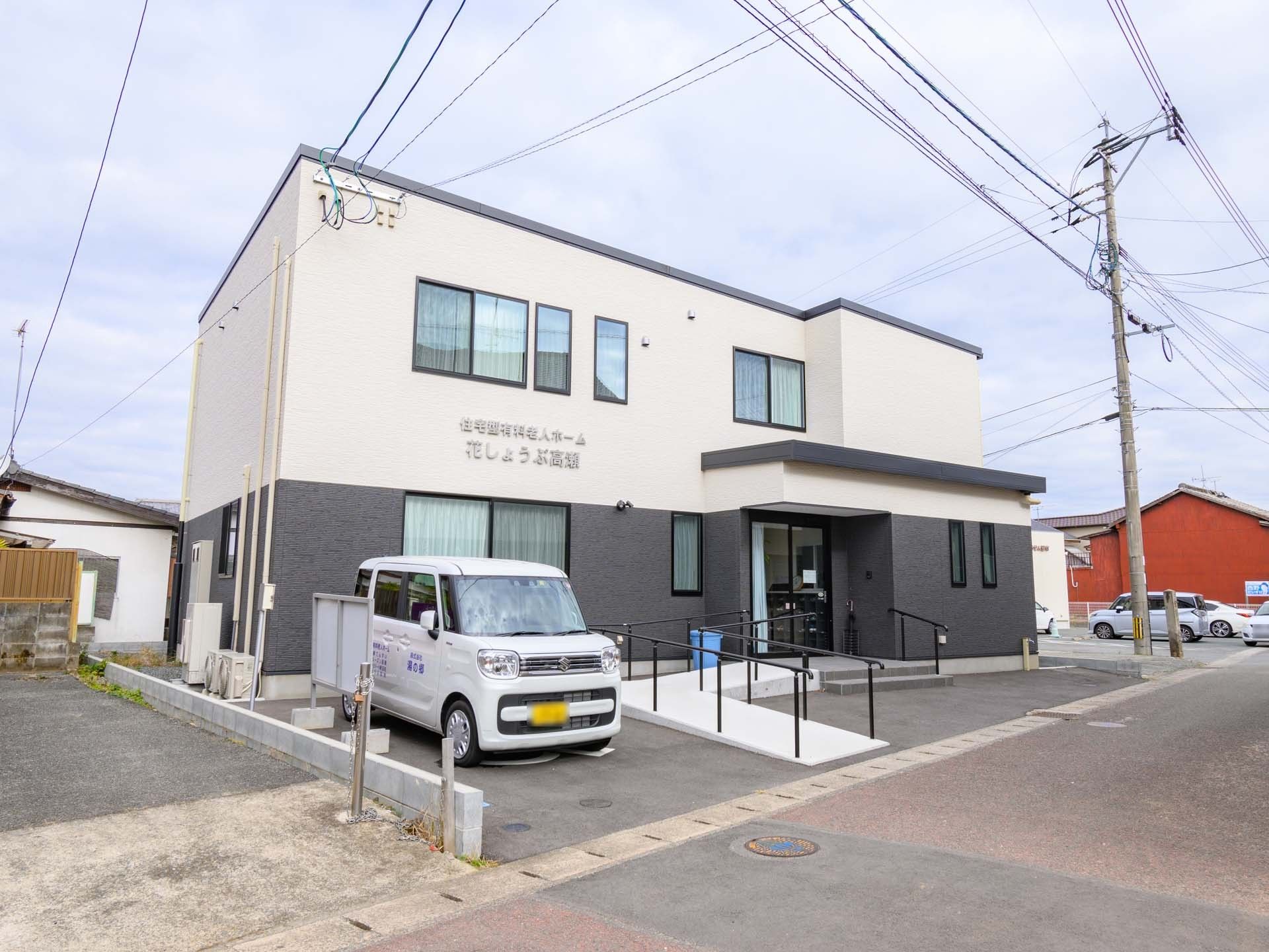 住宅型有料老人ホーム花しょうぶ高瀬と書かれたツートンカラーの壁の2階建て建築物