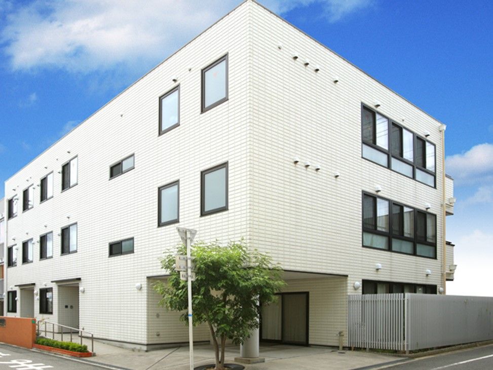 入り口にスロープが設置されている白壁の3階建てグループホーム