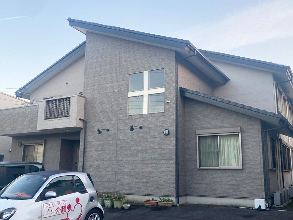 2階の窓に十字架がかけられている茶色い壁で三角屋根の2階建て建築物