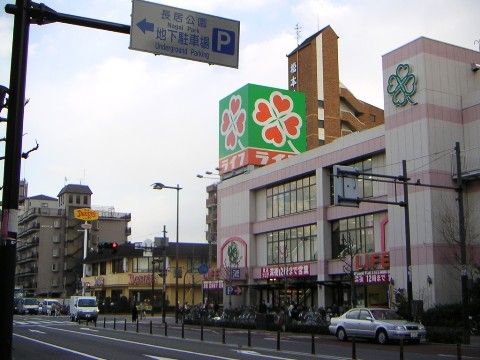 近隣にあるスーパーの外観である。大きな道路に面したスーパーの屋上には、シンボルマークと名前の付いた看板がある。