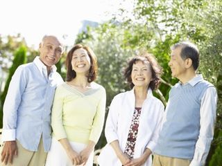 晴れた天気のもと、ご高齢な男女4名が親しげに会話をしている。