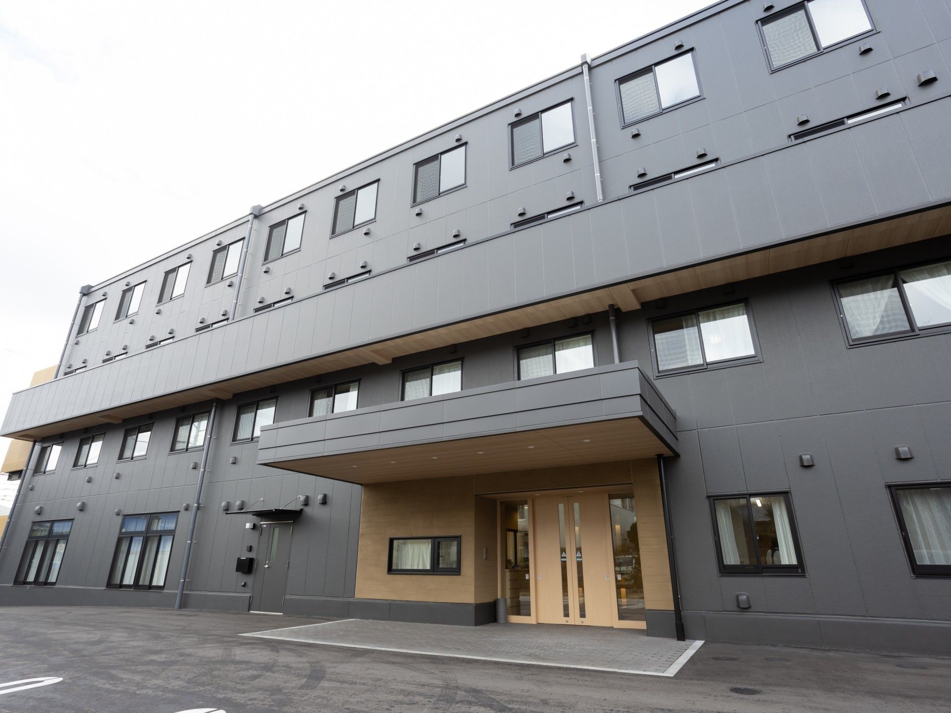 目の前に電柱がある、グレーの外観の4階建て有料老人ホーム