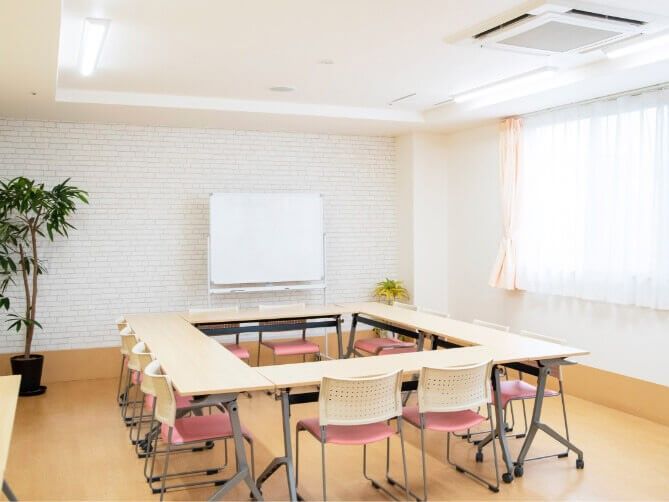 ホワイトボードがあり長机が四角にセットされ、いすも設置されている共有スペース