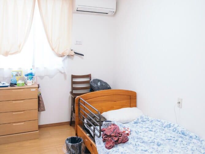 介護用ベッドと収納家具、いす、ごみ箱が置かれている個室