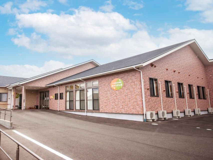 入り口にスロープがあり、レンガ調の外壁で三角屋根の平屋建てグループホーム