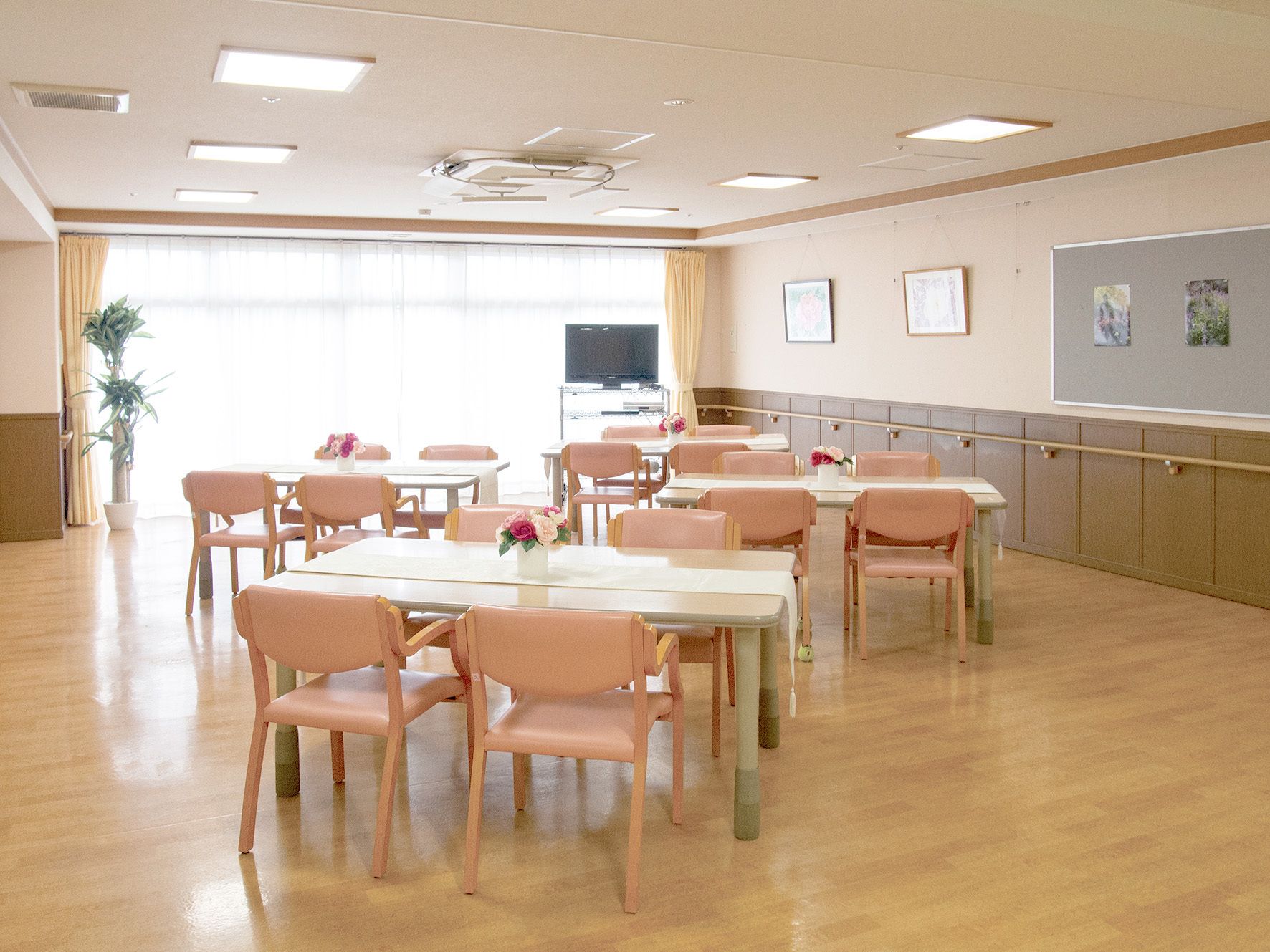廊下に面してリビングがある。机を囲むように椅子が設置されている。テレビの周りにはソファが置かれている。奥に洗面台がある