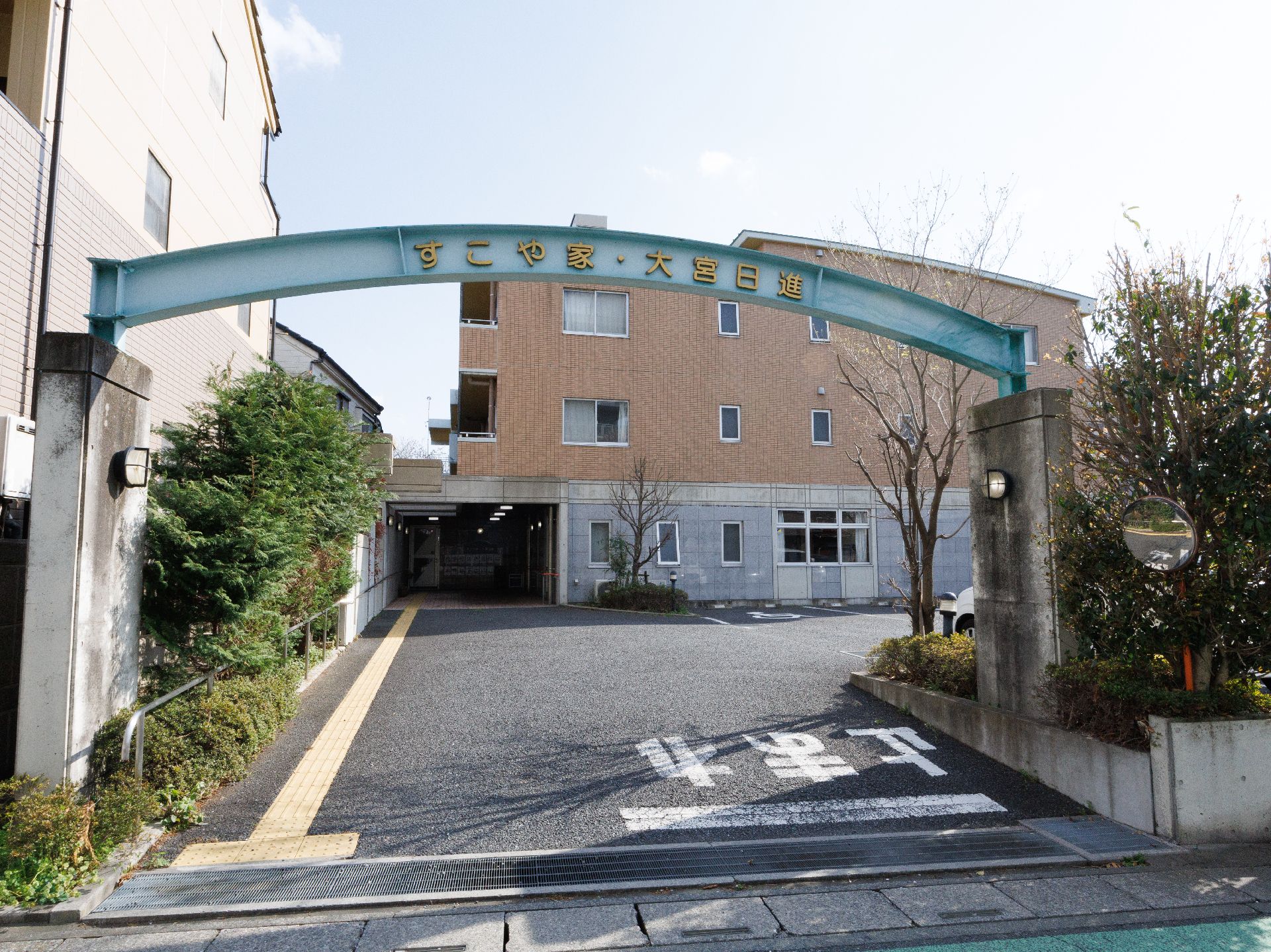 敷地入口から玄関までは舗装され、植栽がある。また点字ブロックがある通路と、手すりも設置してある。建物横には駐車スペースがある。