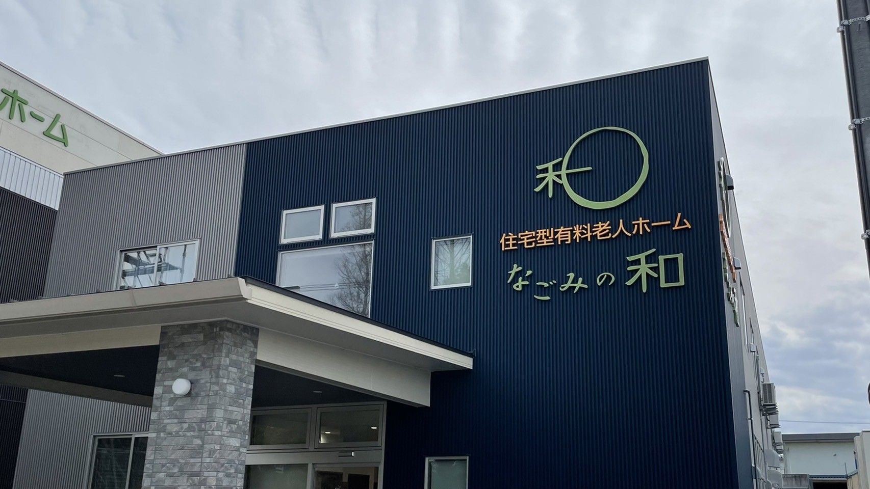 紺色と細いストライプの外壁の2階建て有料老人ホーム