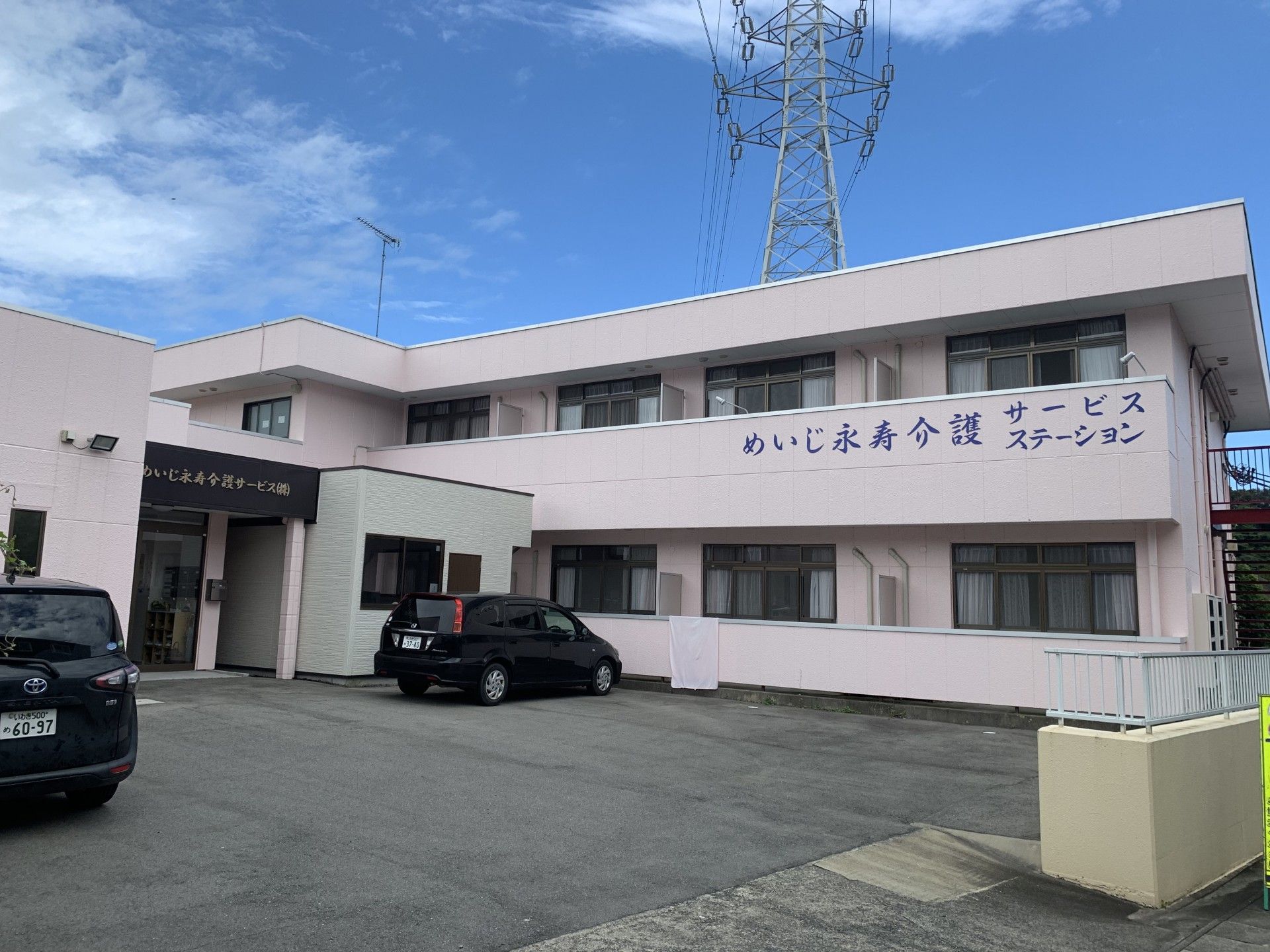 めいじ永寿介護サービスステーションと書かれているピンク色の外壁の2階建て老人ホーム