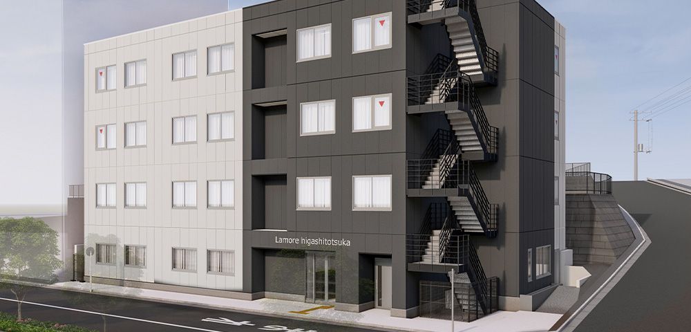 白と黒を基調とした外観の四階建ての建物。施設周囲は舗装されている