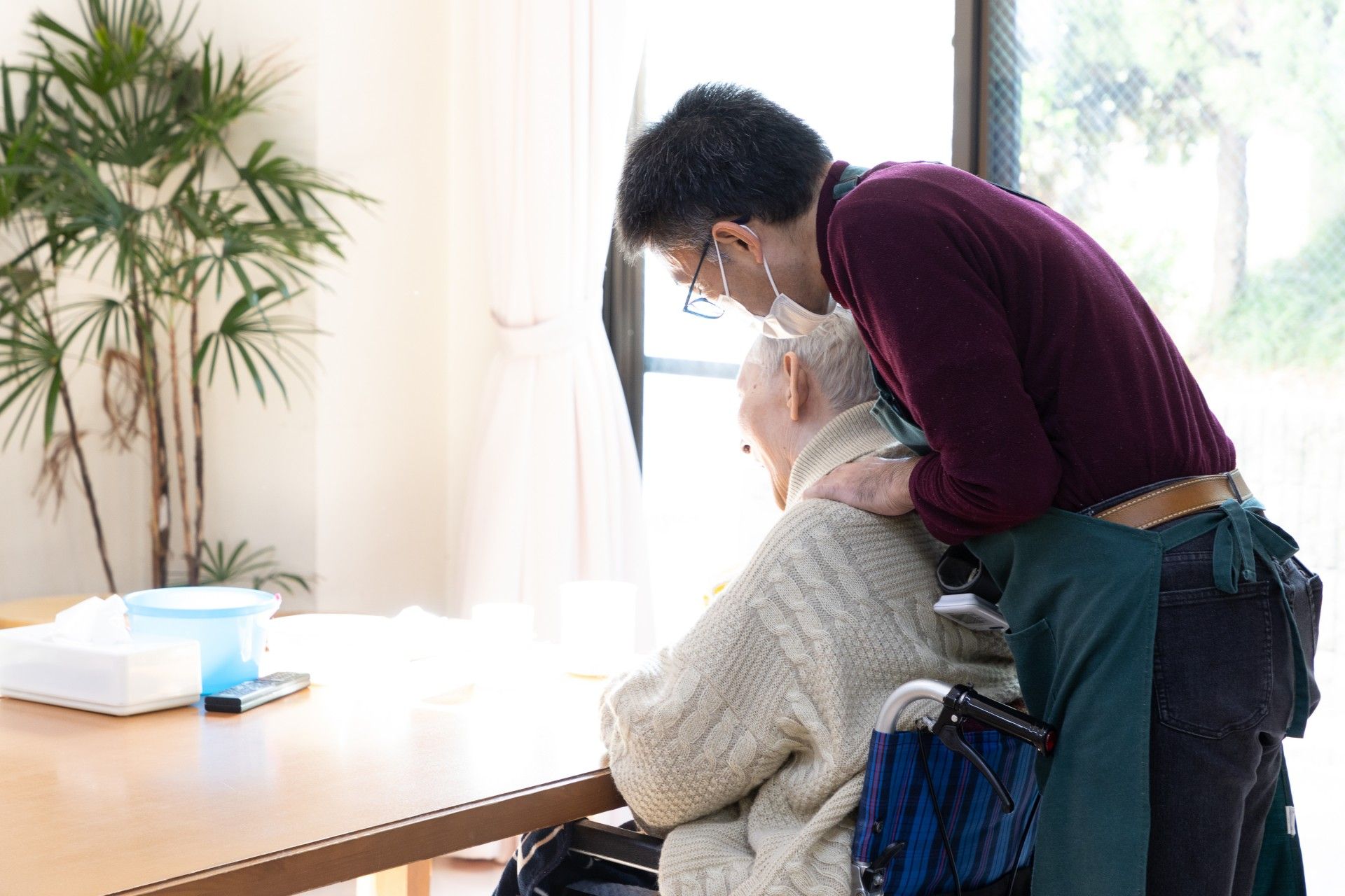 メガネをかけた高齢の男性がソファーに座りながら微笑みかけている様子。