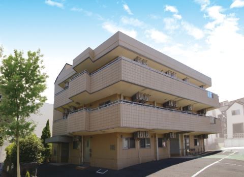 2階と3階にバルコニーがある茶色い壁の3階建てグループホーム