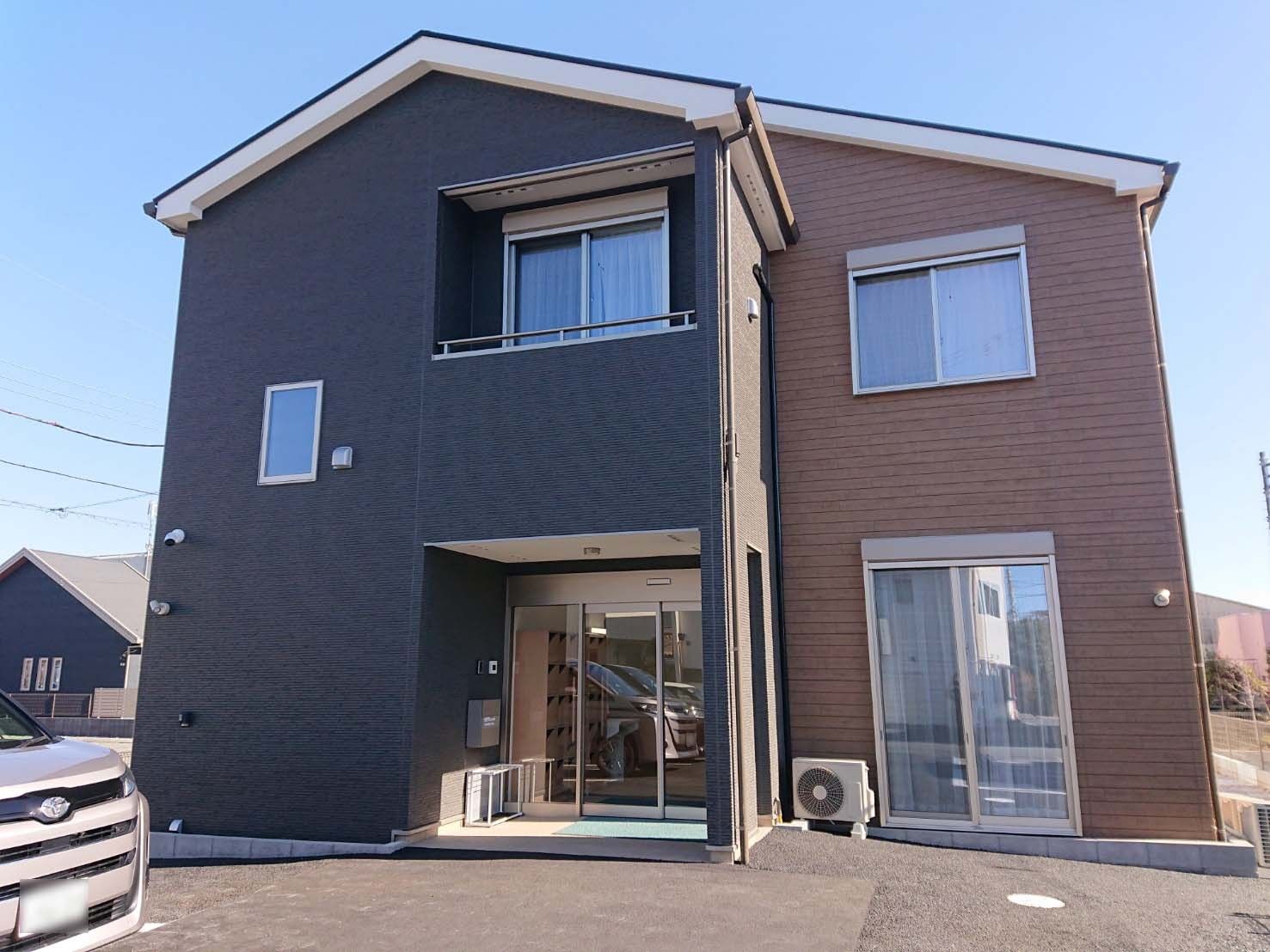 茶色とグレーの外壁で三角屋根の2階建て老人ホーム。