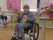 記念品を受け取ってVサインをする車椅子の女性