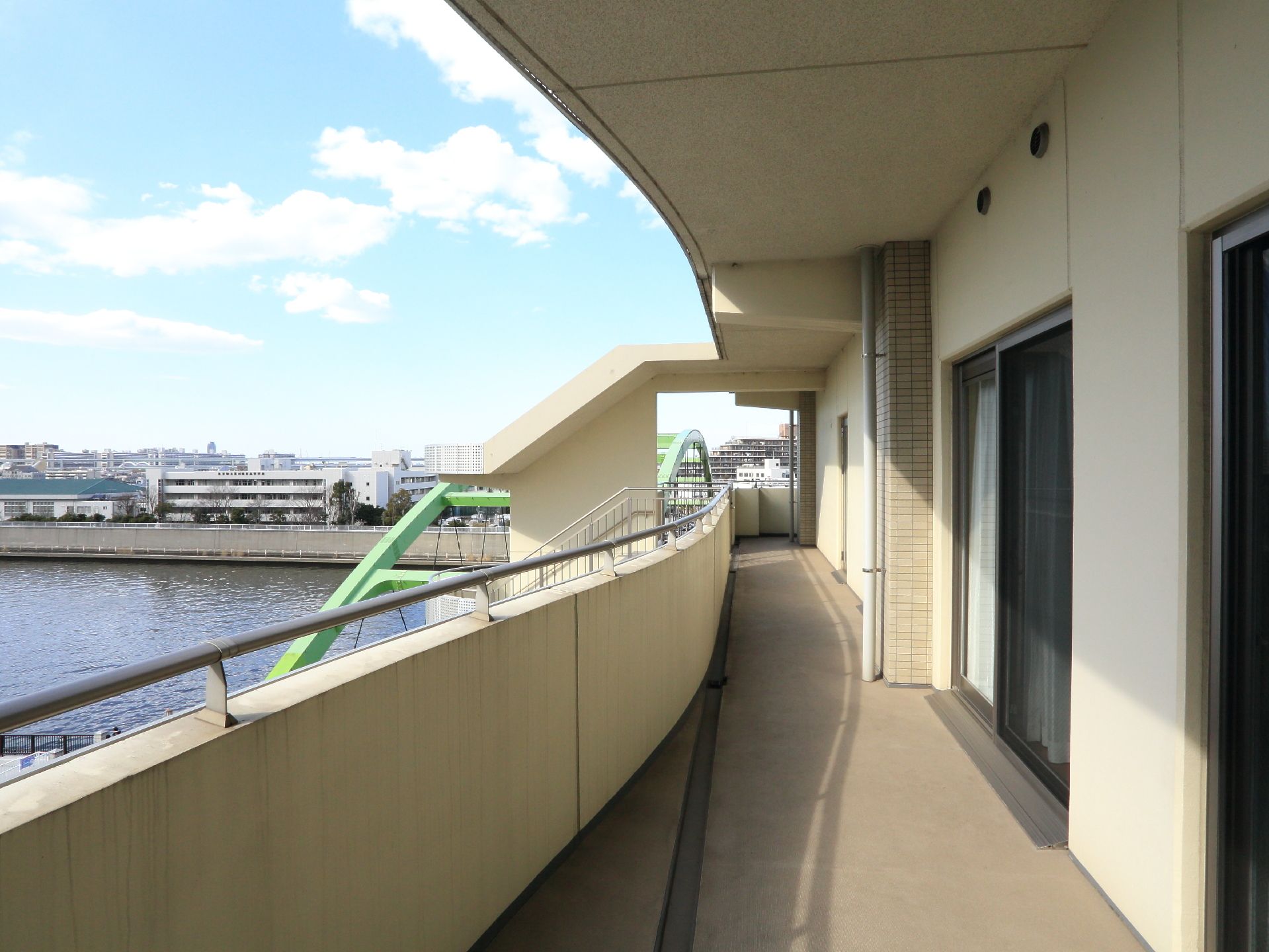 各部屋の外のベランダの様子である。明るい日差しと、施設の近くには川が流れ、すがすがしい景色が広がる。