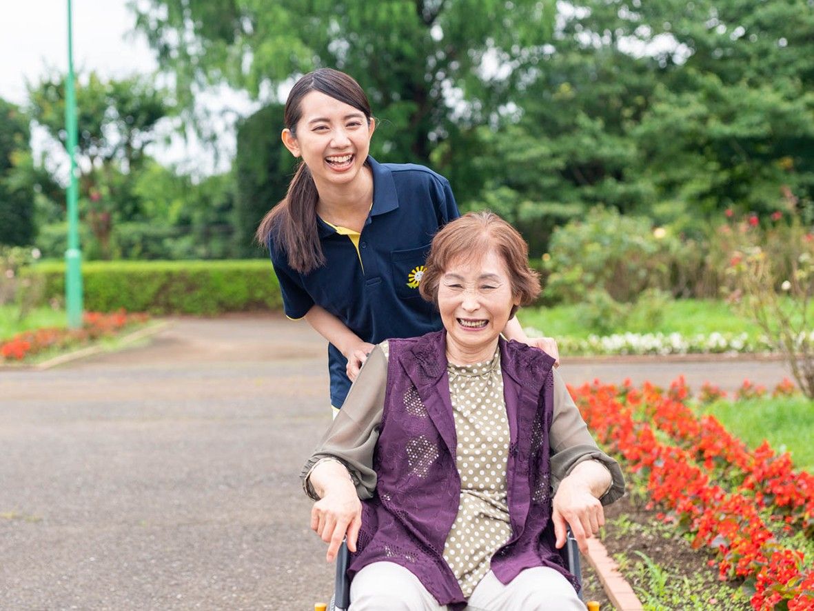 笑顔で外を歩く高齢者とスタッフ
