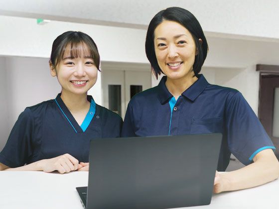 受付カウンターで笑顔を見せる制服姿の女性