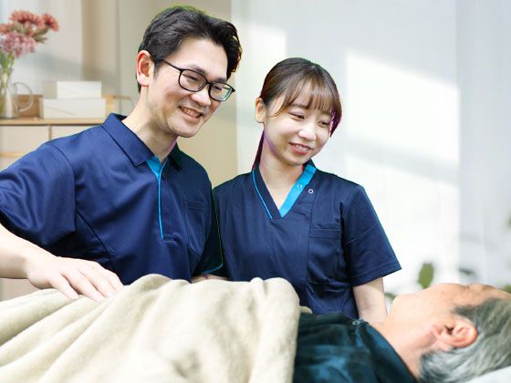 ベッドから体を起こしている高齢の男性とお見舞いの家族